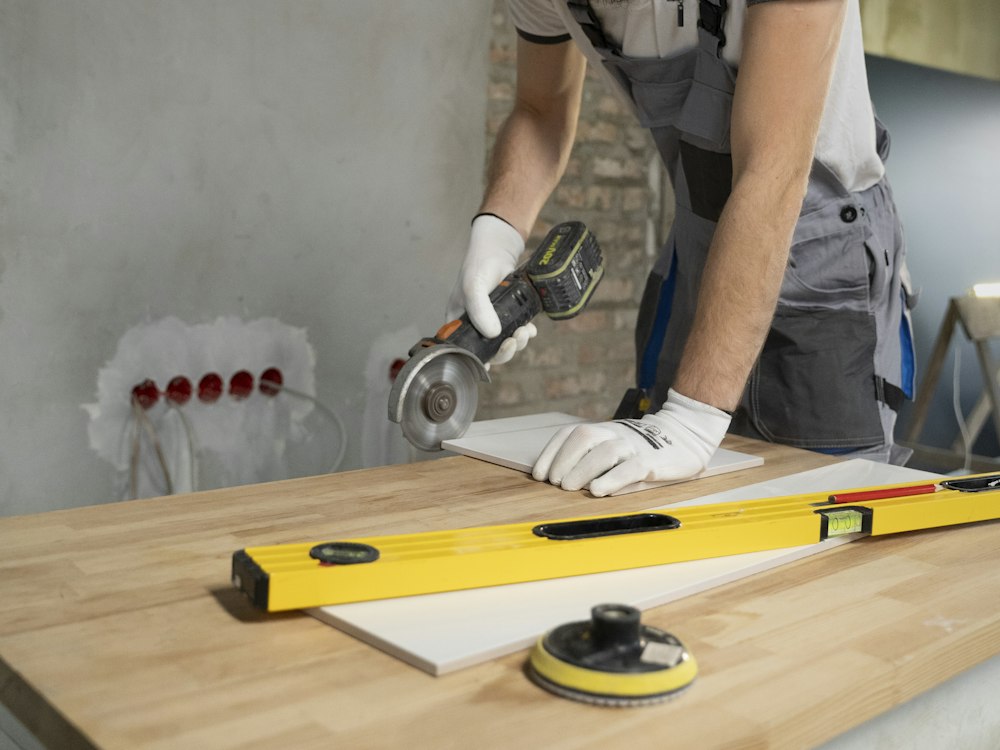 Artisan en salopette découpant un carreau à la meuleuse sur un chantier de rénovation